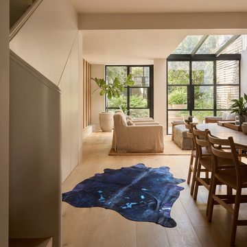 Navy Blue metallic cowhide rug styled on the pale oak floor of a warm contemporary open-plan living room