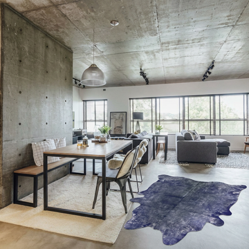 Indigo metallic cowhide rug styled on the concrete floor of an industrial loft dining space