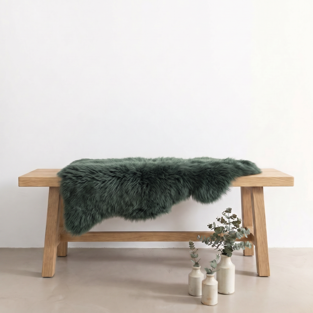 Jungle Green single sheepskin rug draped over a wooden bench in a styled interior
