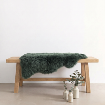 Jungle Green single sheepskin rug draped over a wooden bench in a styled interior