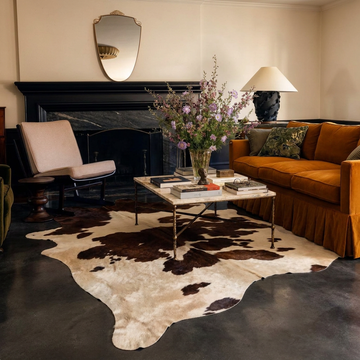 Caramel and ivory exotic printed cowhide rug styled on the floor of an editorial interior