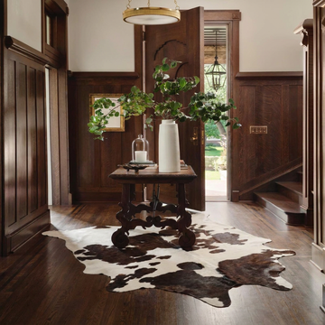 Caramel and ivory exotic printed cowhide rug styled on the floor of an editorial interior