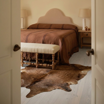 Caramel and ivory exotic printed cowhide rug styled on the floor of an editorial interior