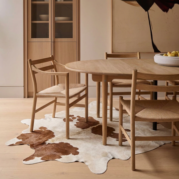Caramel and ivory exotic printed cowhide rug styled on the floor of an editorial interior