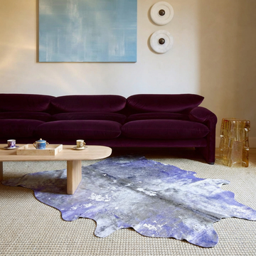 Violet and Grey metallic cowhide rug styled in front of a plum velvet sofa in a warm contemporary lounge