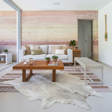 Ivory speckled cowhide rug styled on the floor of a soft blush-pink living room