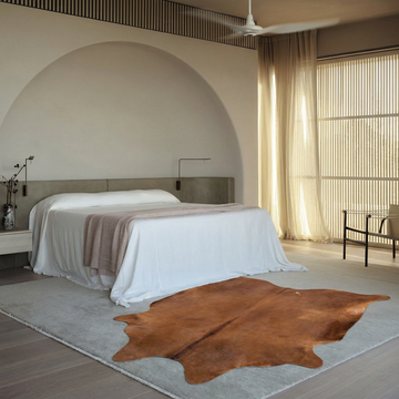 Warm caramel solid natural cowhide rug styled on the floor of an editorial interior