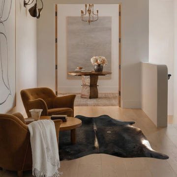 Caramel and ivory exotic printed cowhide rug styled on the floor of an editorial interior