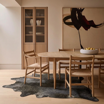 Gold speckled metallic cowhide rug styled under a round oak dining table in a japandi dining room