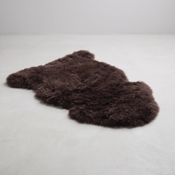 Chocolate single sheepskin rug laid flat on a pale grey floor