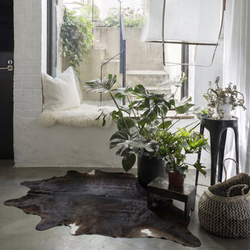 Espresso solid cowhide rug styled on the floor of a boho window-seat nook