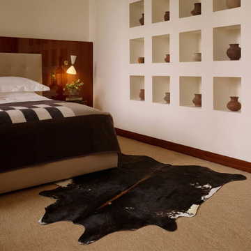 Caramel and ivory exotic printed cowhide rug styled on the floor of an editorial interior