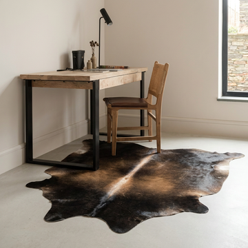 Natural cowhide rug styled on the floor of an editorial interior room