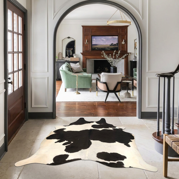 Black and white Holstein Brazilian cowhide rug styled on the pale stone floor of an elegant arched hallway