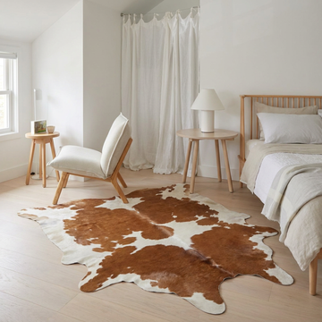 Caramel and ivory exotic printed cowhide rug styled on the floor of an editorial interior