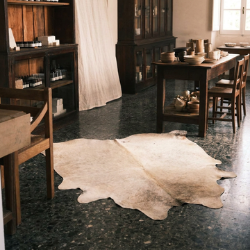 Caramel and ivory exotic printed cowhide rug styled on the floor of an editorial interior