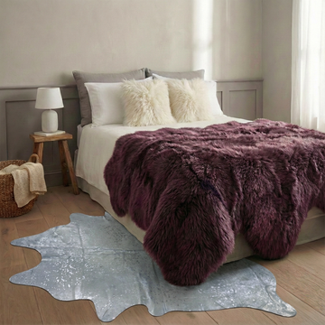 Silver on off-white metallic cowhide rug styled on the pale oak floor of a grey-panelled minimal bedroom