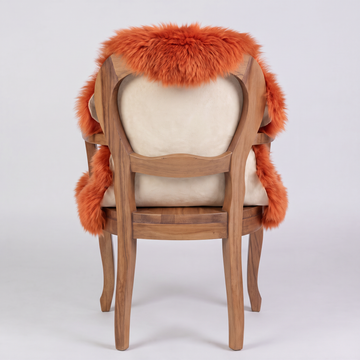 Burnt Orange single sheepskin rug over the back of a wooden armchair, rear view