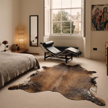 Mocha, chocolate and ivory cowhide rug styled on the floor of an elegant Georgian bedroom