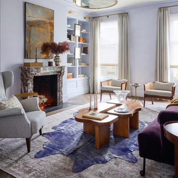 Purple metallic cowhide rug styled on the floor of a lilac soft-glam living room with aubergine velvet sofa