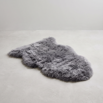 Grey single sheepskin rug laid flat on a pale grey floor