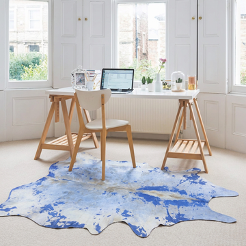 Blue acid wash cowhide rug styled in front of a trestle desk in a bright Scandinavian home office
