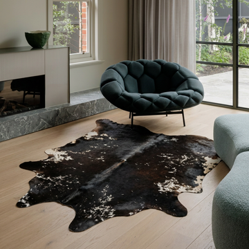 Caramel and ivory exotic printed cowhide rug styled on the floor of an editorial interior