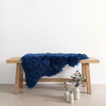 Cobalt Blue sheepskin rug draped over an oak bench in a minimal interior