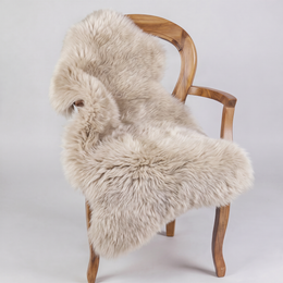 Oyster sheepskin rug draped over a wooden armchair, front three-quarter view