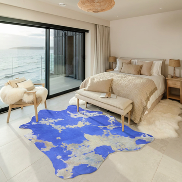 Cobalt blue acid wash cowhide rug styled on the stone floor of a coastal bedroom with sea views