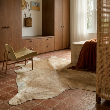 Caramel and ivory exotic printed cowhide rug styled on the floor of an editorial interior