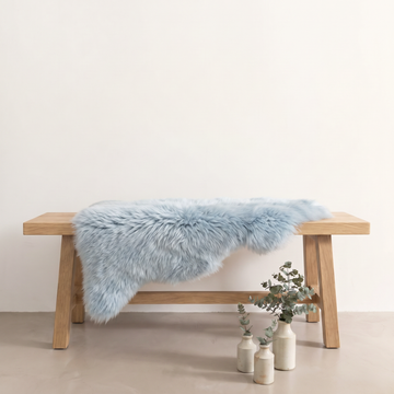 Sea Foam sheepskin rug draped over an oak bench in a minimal interior