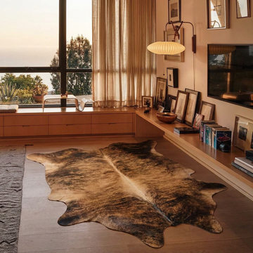 Exotic brindle cowhide rug styled on the floor of a warm mid-century living room with wood ceiling