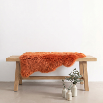 Burnt Orange single sheepskin rug draped over a wooden bench in a styled interior