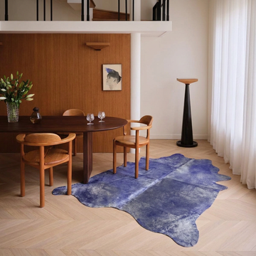 Violet metallic cowhide rug styled on pale herringbone parquet in a contemporary loft dining space