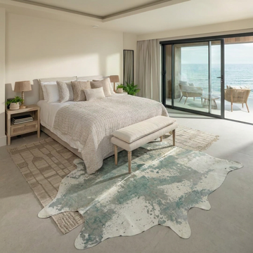 Platinum acid wash cowhide rug styled at the foot of the bed in a serene coastal bedroom