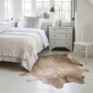 Caramel and ivory exotic printed cowhide rug styled on the floor of an editorial interior