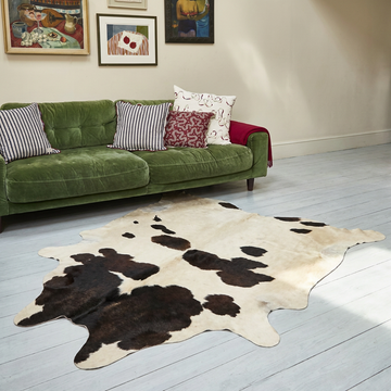 Caramel and ivory exotic printed cowhide rug styled on the floor of an editorial interior