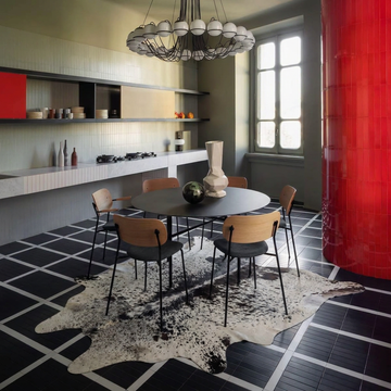 Black salt and pepper cowhide rug styled under the dining table of a monochrome contemporary kitchen-diner