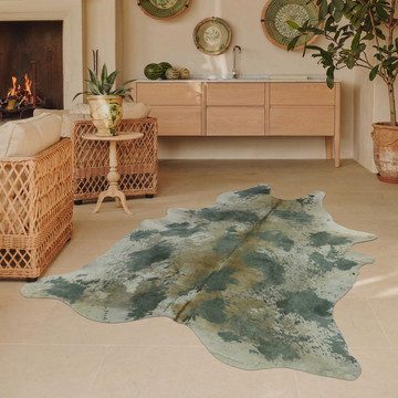 Acid-wash sage green cowhide rug styled on the limestone floor of a warm Mediterranean sitting room