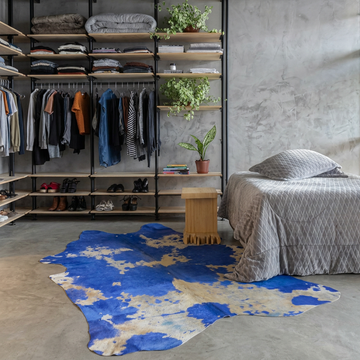 Cobalt blue acid wash cowhide rug styled on the polished concrete floor of an industrial loft bedroom