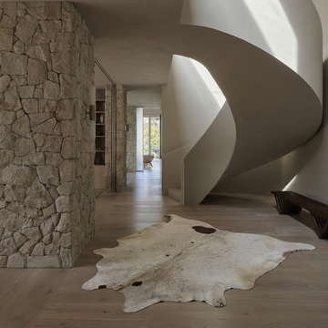 Caramel and ivory exotic printed cowhide rug styled on the floor of an editorial interior
