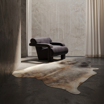 Caramel and ivory exotic printed cowhide rug styled on the floor of an editorial interior