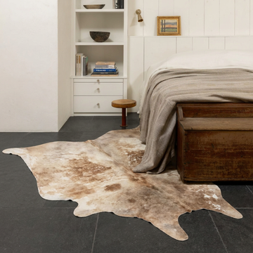 Caramel and ivory exotic printed cowhide rug styled on the floor of an editorial interior