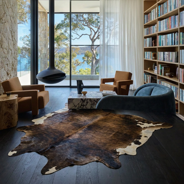 Caramel and ivory exotic printed cowhide rug styled on the floor of an editorial interior