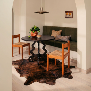 Dark brindle cowhide rug styled on the floor of an editorial interior