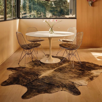 Exotic brindle cowhide rug styled on the floor of a mid-century breakfast nook with wire chairs