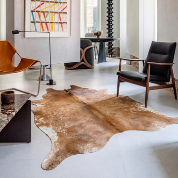 Caramel and ivory exotic printed cowhide rug styled on the floor of an editorial interior
