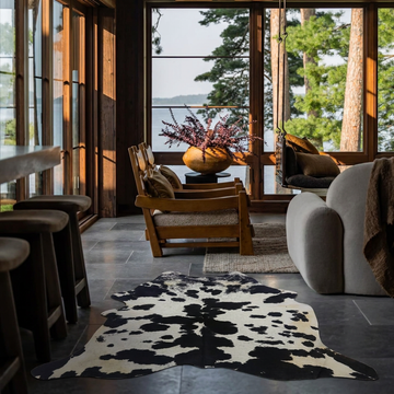 Black and white cowhide rug styled on the grey slate floor of a modern lakeside living room