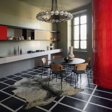 Black and white speckled cowhide rug styled on the tiled floor of an industrial monochrome dining room
